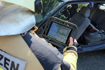 technisches Gerät zeigt gescanntes Übnungsauto an, Feuerwehrmitarbeiter wertet es aus
