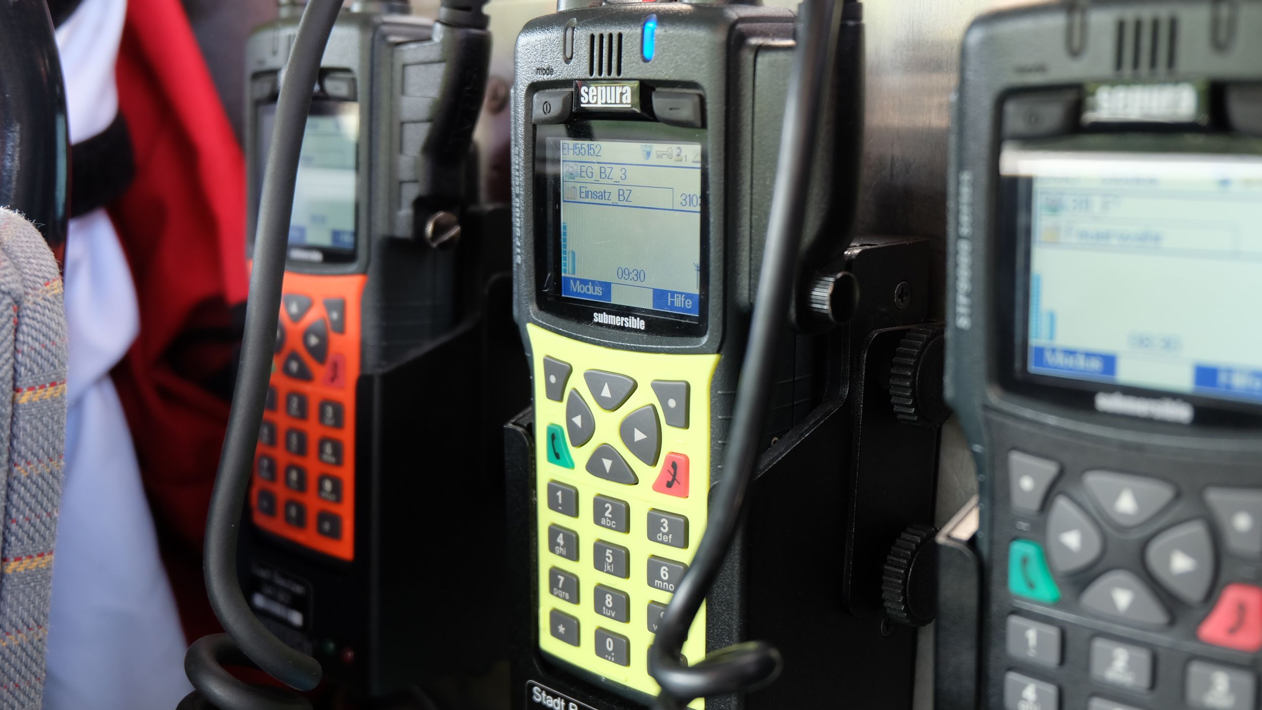 Drei Funkgeräte in schwarzer, gelber und roter Farbe